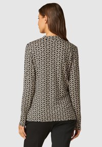 Black and beige long-sleeve shirt featuring a geometric pattern, crew neck, and a smooth, soft texture. Fits closely to the body.