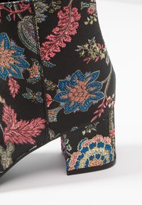 Czarne botki za kostkę z kwiatowym wzorem w odcieniach różu, niebieskiego i złotego. Posiadają słupkowy obcas oraz teksturowany materiał z misternymi haftami.