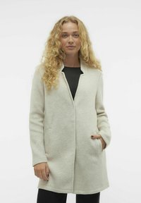 Cappotto in feltro grigio chiaro con taglio dritto, tasche laterali e colletto notch, caratterizzato da una texture liscia e un design minimalista.