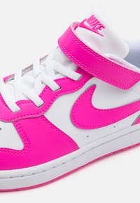 Höga sneakers i vit läder med klara rosa detaljer. Har ett rosa rem, vita snören och en texturerad gummisula.