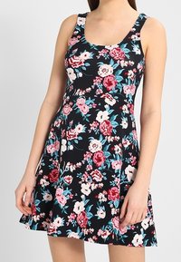 Robe fleurie avec un fond noir orné de fleurs roses, rouges et bleu sarcelle. Confectionnée dans un tissu léger, elle possède un corsage ajusté et une jupe évasée.