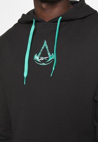 Felpa nera con lacci turchesi. Presenta un design ricamato turchese di un'ancora e di un triangolo sul petto. Tessuto in misto cotone.