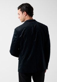 Zwarte fluwelen blazer voor mannen, met een strak ontwerp, een gladde textuur, een op maat gemaakte pasvorm en subtiele patroon details op de stof.