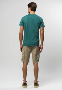 Teal kortärmad t-shirt med rundad halsringning, i kombination med beiga cargo-shorts med flera fickor och en avslappnad passform.