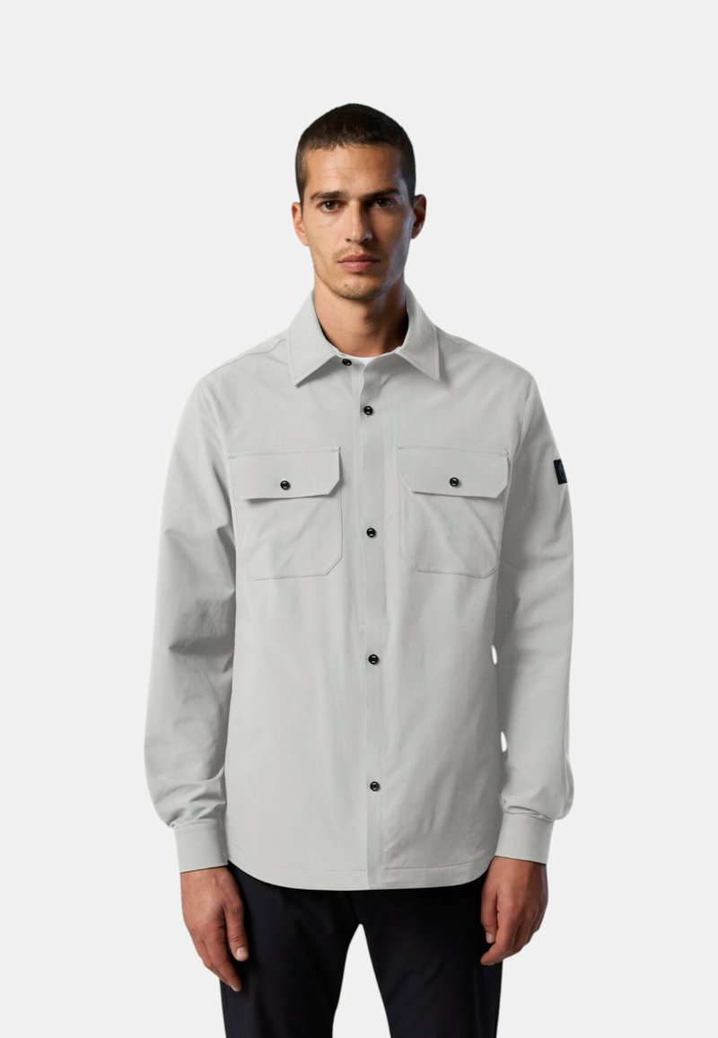 Camicia grigia chiaro con maniche lunghe, due tasche sul petto, chiusura frontale con bottoni e dettagli neri sui bottoni. Il tessuto sembra liscio e resistente.