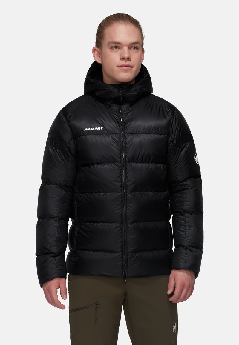 Svart dunjacka med huva, med dragkedja fram, quiltat mönster och logo på vänster bröst. Texturerad tyg med slät finish.