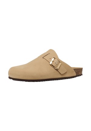 Zueco beige tipo slip-on con una correa ajustable con hebilla dorada, plantilla de corcho contorneada y suela negra texturizada para mayor agarre.