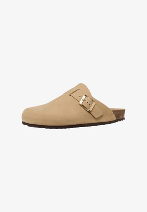Beige slip-on klomp met een verstelbare gouden gespsluiting, gevormd kurken voetbed en een zwarte, getextureerde zool voor grip.