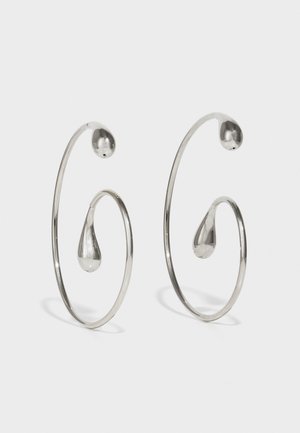 Boucles d'oreilles en argent en forme de créole avec un design en spirale, mettant en avant des accents en forme de goutte d'eau. Texture lisse et réfléchissante avec une esthétique minimaliste.