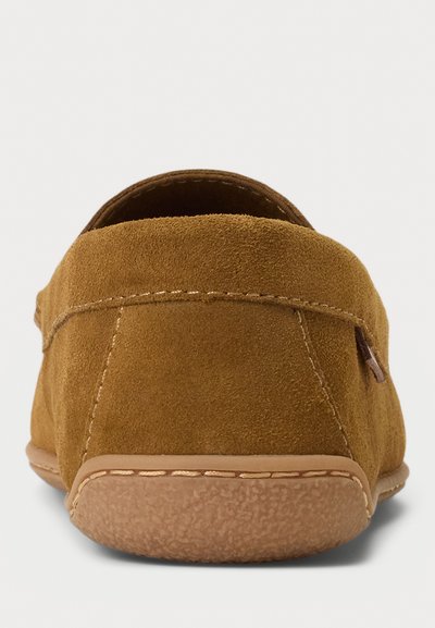 Scarpe slip-on in suede marrone con retro arrotondato, caratterizzate da una suola testurizzata e cuciture a contrasto lungo il bordo. Finitura liscia.