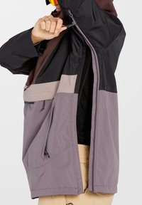 Farbenfrohe, leichte Jacke mit einem Mix aus schwarzen, braunen und lavendelfarbenen Stoffen. Verfügt über Reißverschlusstaschen und einen verstellbaren Saum.