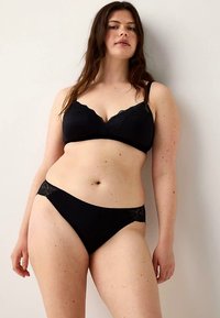 Svart underklädesset med en spetskantad bralette och matchande trosor, båda gjorda av mjukt tyg med en slät textur och minimalistisk design.