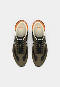 Turnschuhe mit einem Farbschema aus Grün, Schwarz und Orange. Aus Wildleder und Textilmaterialien, mit grauen Akzenten, rundem Zehenbereich und Schnürsenkeln.