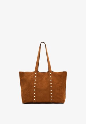 Braune Kunstwildleder-Tote-Tasche mit zwei langen Griffen, die vertikale Reihen von silberfarbenen Nieten auf der Vorderseite aufweist. Geräumiges rechteckiges Design.