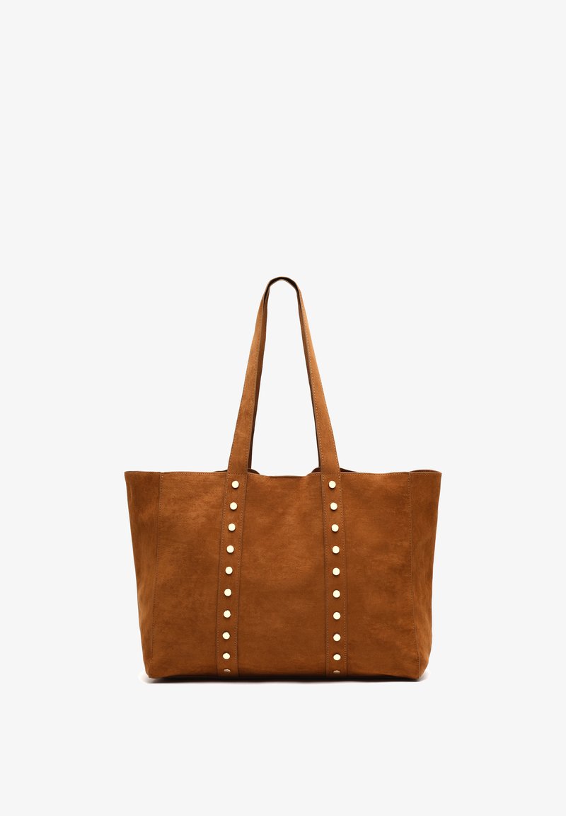 Bruine faux suede schoudertas met twee lange handvatten, versierd met verticale rijen zilverkleurige studs aan de voorkant. Ruimtelijk rechthoekig ontwerp.