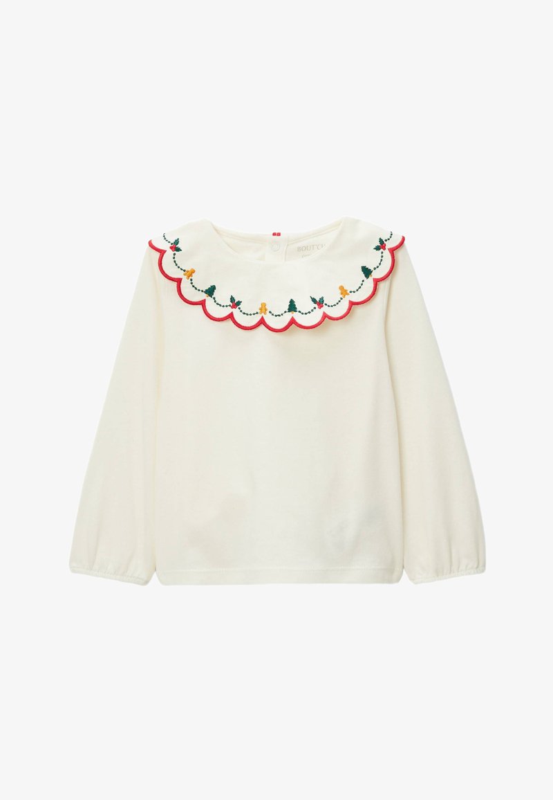 Chemise blanche à manches longues avec un col rouge festonné, décorée de broderies vertes et jaunes représentant des arbres et des personnages en pain d'épice.