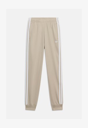 Beige Trainingshose mit elastischem Bund, zwei Vordertaschen, weißen Seitenstreifen und kleinem weißen Adidas-Logo am linken Oberschenkel.