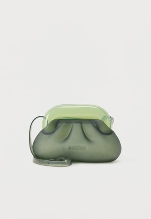 Mala zelena prozirna torbica s naboranim dizajnom, podesivim remenom i logotipom "melissa" na prednjoj strani.