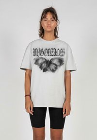Lys grå oversized t-skjorte med svart sommerfugl grafikk og tekst. Kombinert med svarte sykkelshorts, enkel design og passform.