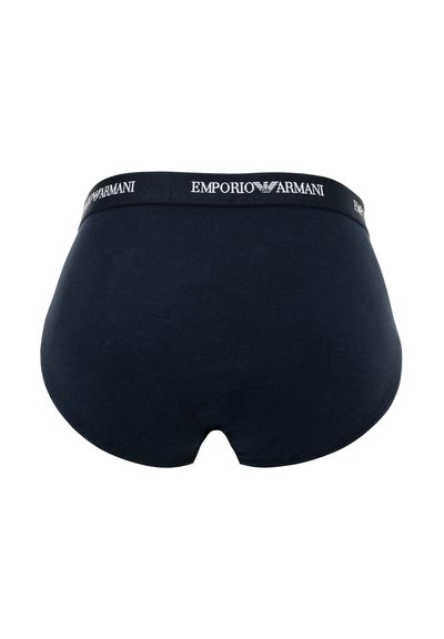 Μαύρο εσώρουχο Emporio Armani με ελαστική μέση που φέρει λευκό λογότυπο της μάρκας και έμβλημα αετού, εμφανιζόμενο από πίσω σε λευκό φόντο.