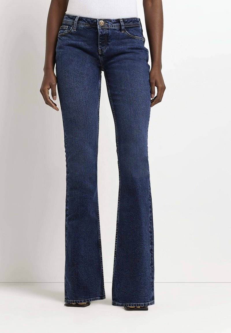Dark blue flared jeans in a denim material, featuring a fitted waist, front pockets, and subtle stitching details along the seams.
