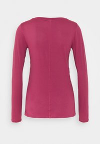 Top z długim rękawem w intensywnym kolorze malinowym, wykonany z fakturowanej siateczkowej tkaniny. Posiada okrągły dekolt i dopasowaną sylwetkę.