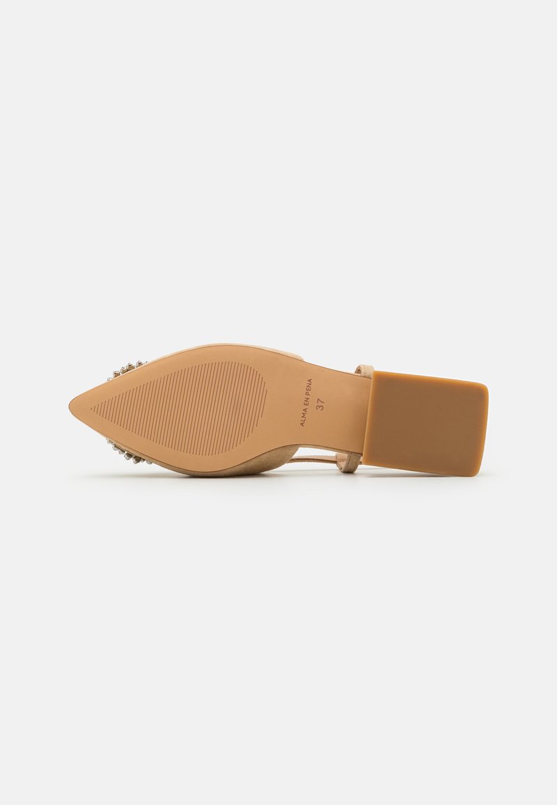 Zapato de tacón alto beige con punta afilada, suela texturizada y tacón cuadrado. Acentos de gemas decorativas en el tacón añaden detalle. Talla 37.