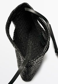 Borsa a tracolla nera intrecciata con spalline in pelle liscia, design a apertura superiore e interno testurizzato. Caratterizzata da una forma cilindrica e accenti minimal.