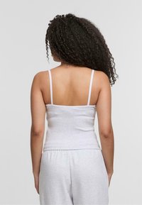 Gray ribbed tank top with thin straps, fitted design, and a smooth texture, viewed from the back, paired with gray sweatpants.