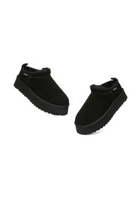 Paar schwarze Slipper-Winterschuhe mit dicken Sohlen und weicher Innenausstattung, schräg auf weißem Hintergrund positioniert.