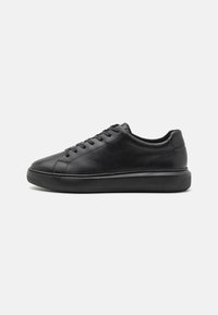 Sneakers neri in pelle con una finitura liscia, punta rotonda, design con lacci e suola in gomma testurizzata. Stile minimalista senza loghi visibili.