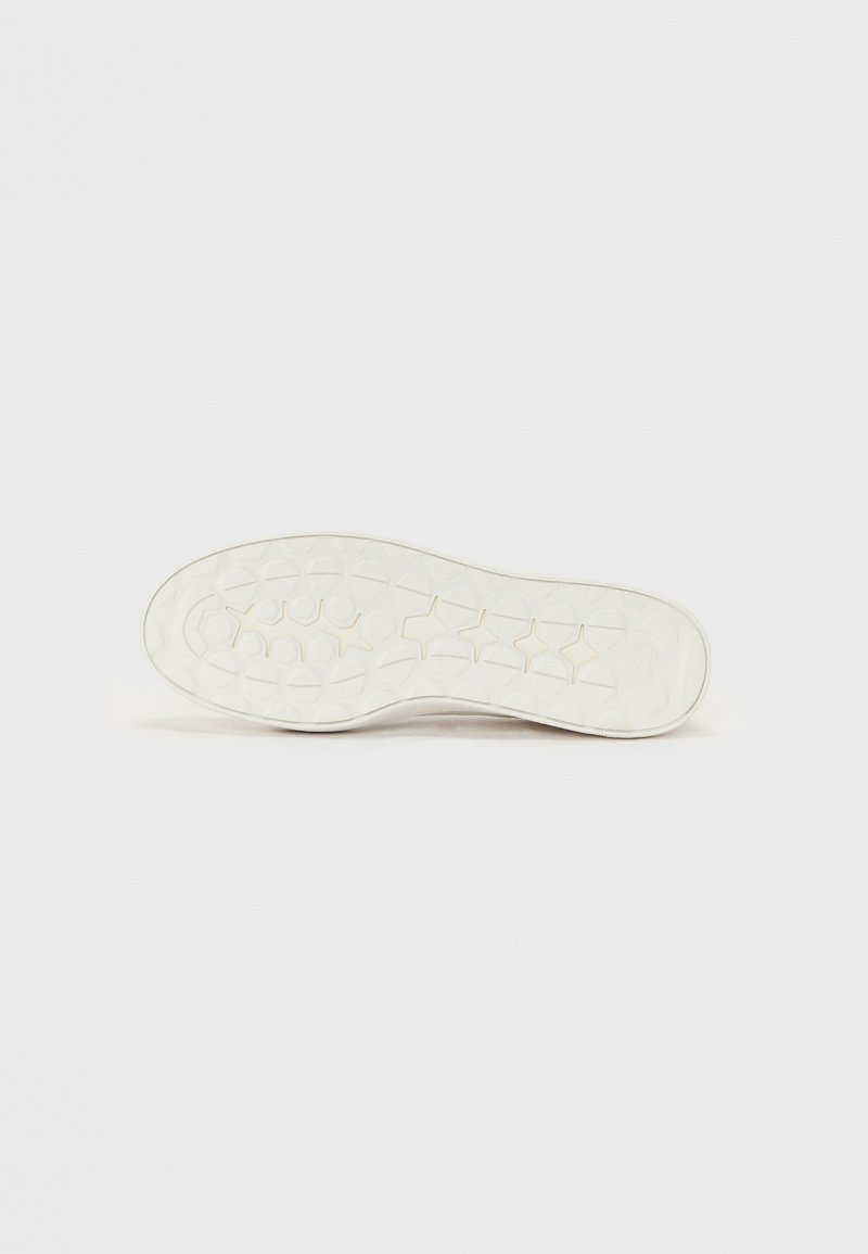 Suela de zapato de goma blanca con un fondo texturizado que presenta patrones circulares y de estrellas para agarre y durabilidad. Bordes suaves y diseño de punta redondeada.