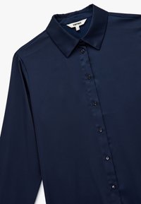 Mørkeblå langærmet skjorte med spidse kraver, frontknapper og glat stoftekstur. Har et klassisk og skræddersyet design.