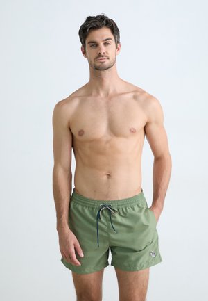 Shorts de bain verts avec une taille élastique, un cordon de serrage et un petit logo brodé sur l'ourlet. Tissu lisse et léger.