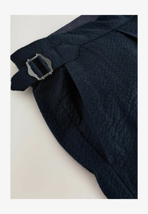 Shorts in tessuto blu navy con superficie testurizzata, dotati di chiusura con fibbia argentata e vestibilità sagomata, con dettagli delle cuciture diagonali.