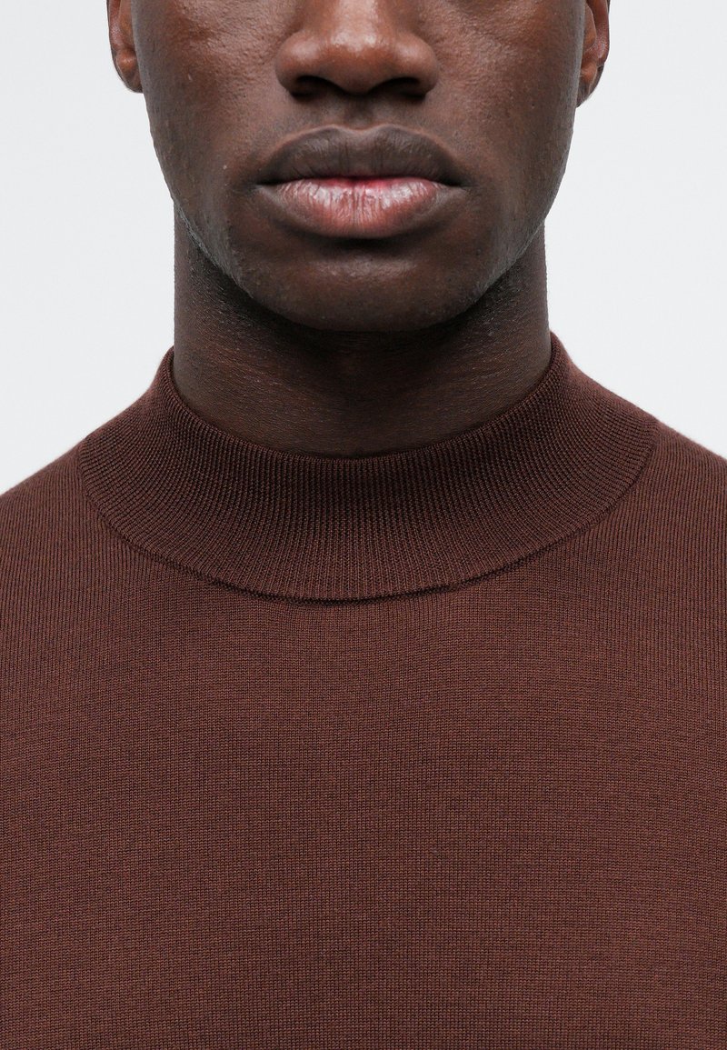 Brun ribbet strikket turtleneck sweater med en tætsiddende pasform, udstyret med en høj krave og en glat tekstur.