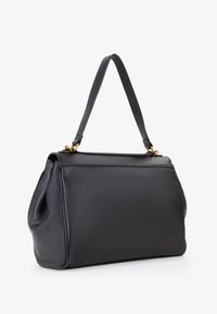 Bolso de piel negra con forma estructurada, una sola asa de hombro y acentos en oro. Textura suave con detalles de grano sutil.