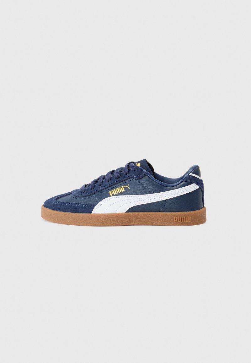 Baskets Puma bleu marine avec bande blanche, semelle en gomme, logo Puma doré sur le côté et sur la languette, vues de profil extérieur sur fond uni.