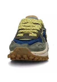 Sneaker verde e blu con materiali in suede testurizzato e tessuto, caratterizzato da lacci intrecciati gialli, una suola spessa e una intersuola maculata.