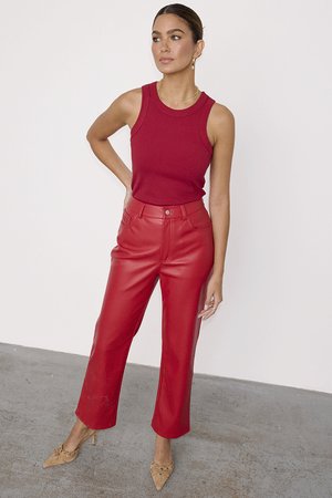 Red sleeveless top paired with high-waisted, wide-leg red faux leather pants. Textured fabric, smooth finish, and pointed tan heels.