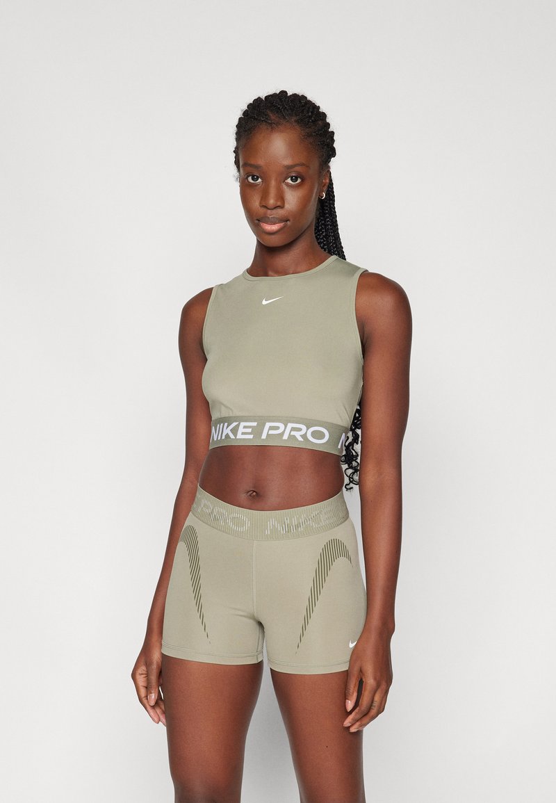 Conjunto deportivo Nike Pro que incluye un top corto sin mangas en color verde oliva y pantalones cortos a juego con una cinturilla texturizada y patrones de líneas sutiles.