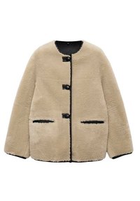 Veste en fausse fourrure beige avec un col rond, trois boutons noirs, deux poches avant et un bord contrastant noir le long des contours.