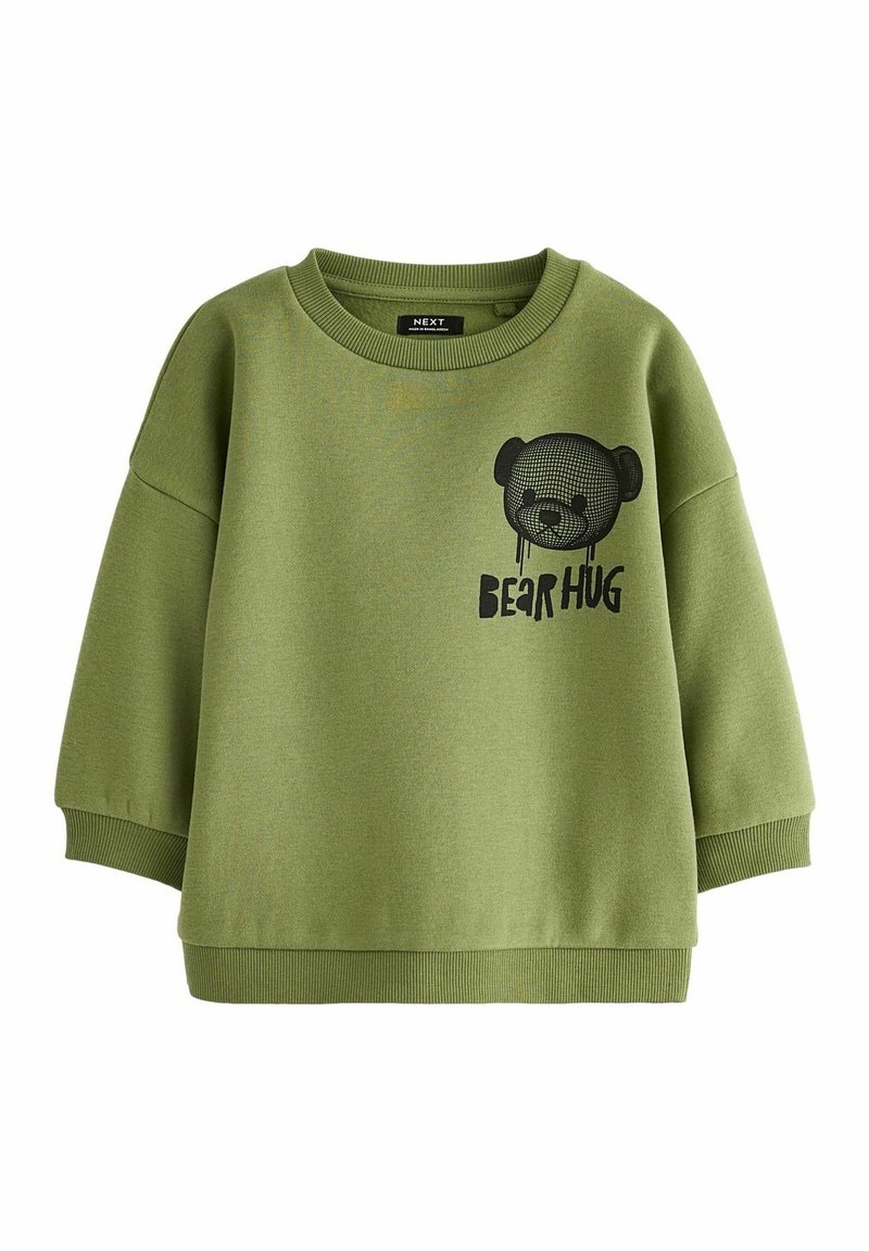Sweat-shirt col rond vert olive avec poignets et ourlet côtelés, présentant un visage d'ours en peluche noir et le texte "BEAR HUG" sur le devant.