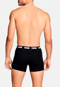 Schwarze Boxershorts aus Baumwolle mit einem breiten elastischen Bund, auf dem "PUMA" in Weiß zu sehen ist. Das Design ist eng anliegend und glatt.
