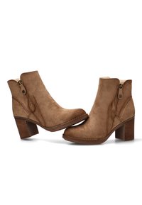 Botas de ante marrón hasta el tobillo con puntera redondeada, cremallera lateral y tacón apilado. Costuras destacadas y un acento de botón en el lado exterior.