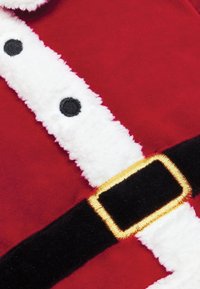 Rødt stof med hvidt, blødt kantbånd, sorte knapper og et sort bælte med en gylden spænde. Designet minder om en julemanddragt.