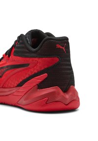 Rote und schwarze Sportschuhe mit einem strukturierten Mesh-Obermaterial, auffälligem Zickzackdesign an der Ferse und einer dicken Gummisohle. Mit Logo-Akzenten.