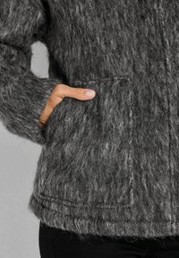 Grijze wollen jas met een gestructureerd, pluizig oppervlak, zijzakken en zichtbare stiksels langs de zoom en naden.