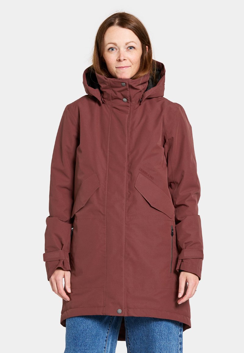 Maroon vattentät jacka med hög krage, justerbar huva och flera fickor. Den har ett texturerat tyg och en avslappnad passform.