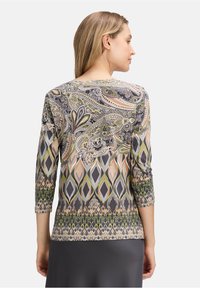 Long-sleeve top in a patterned fabric featuring paisley and diamond designs in gray, green, and peach tones with a round neckline.